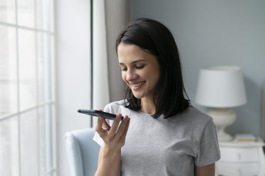Woman smiling during a phone wellness check, representing support and connection for participants receiving disability services in Sydney.
